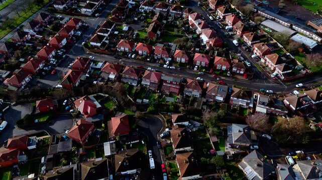 aerial drone shot high angle over the Millbrook suburban housing area estate in Southampton at sunset with trees, homes and nature surrounding. Shot in winter with traffic and cars driving the streets