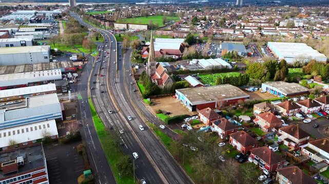 aerial drone shot high angle over the Millbrook suburban housing area estate in Southampton at sunset with trees, homes and nature surrounding. Shot in winter with traffic and cars driving the streets