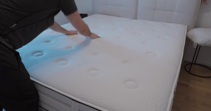 Man hitting and shaking a mattress surface by hand to remove dust and refresh bedding, illustrating home cleaning routine, hygiene and bedroom maintenance concepts.