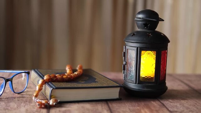 Islamic book with prayer beads and lantern on wooden table, slow motion reveal for Ramadan celebration