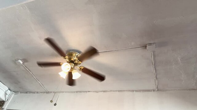 Brass Ceiling Fan with Light Bulbs Spinning on White Ceiling