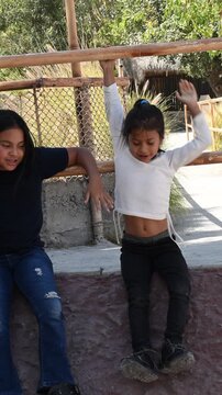 Latina girl playing at sliding on the stones.