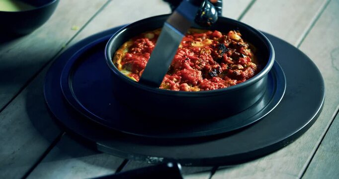 Cook removing round pizza from tray and cutting it up - high, closeup shot