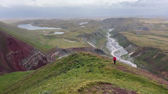 Woman dressed red jacket walking with Tulpar-Kol lake on background Pamir mountain trekking. Lenin peak climbing acclimatization route near 3600m Base Camp, Kyrgystan, Central Asia 4K video.