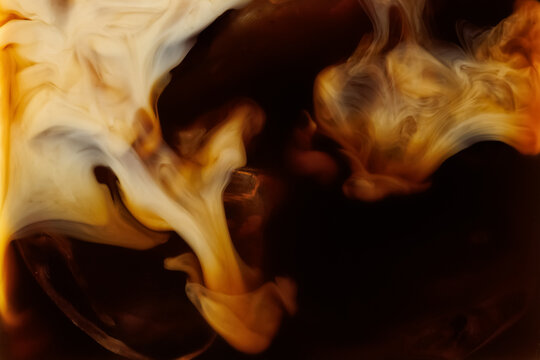 Macro shot of milk mixing into coffee with ice