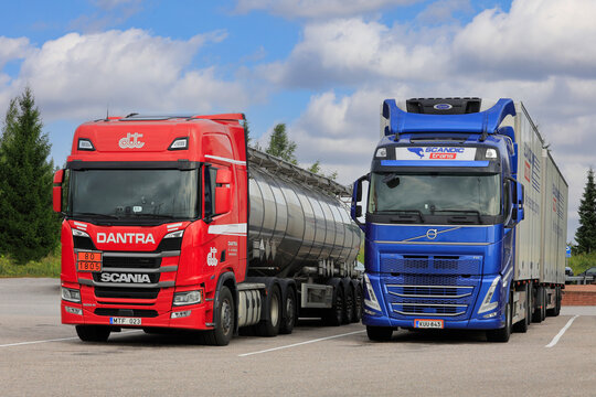 Red Scania R and Blue Volvo FH Heavy Trucks Parked at Truck Stop, Front View.