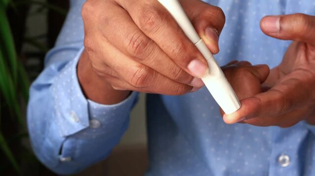 Close up shot of man checking his blood sugar level with a glucometer at home, diabetes testing in slow motion dynamic clip