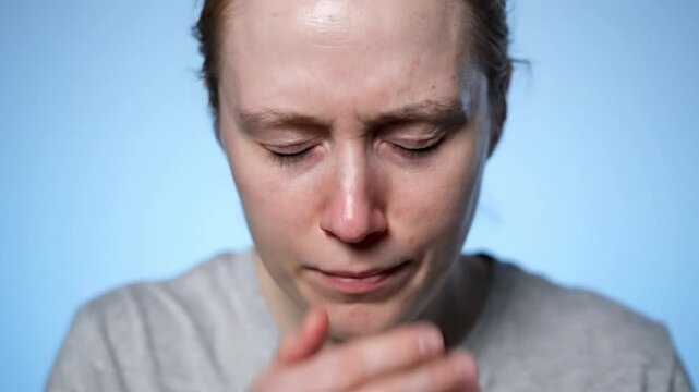 Ultra realistic cinematic medium close video of adult person sneezing with hand covering mouth pale skin tone slight redness near nose tired eyes natural reflex motion during sneeze clean solid studio
