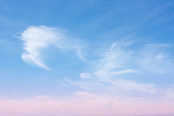 Soft blue sky with delicate white cirrus cloud wisps and pale pink horizon creating calm serene atmosphere at sunrise or sunset