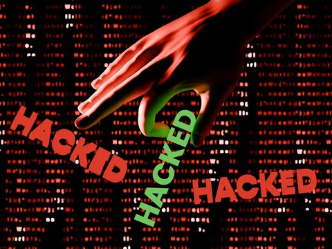 Concept of cybersecurity breach with hand and hacked text over red digital code background.