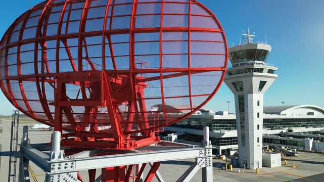 Red radar dish at airport with control tower