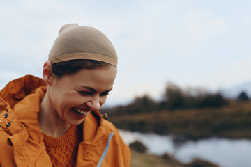 Smiling woman lifestyle outdoors wears orange jacket and beige hairnet, enjoying natural...