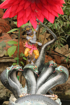 Lord Krishna dancing triumphantly on the heads of multi-headed serpent demon Kaliya, victory of good over evil, Hindu mythology art for fantasy book cover and cultural illustration