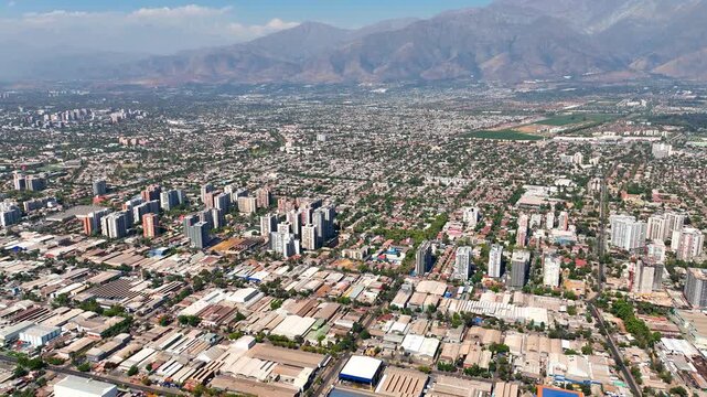 Aerial drone shot panning right over Santiago, Chile, showing Macul, Penalolen, and Las Condes districts with the Andes Mountains in the background.