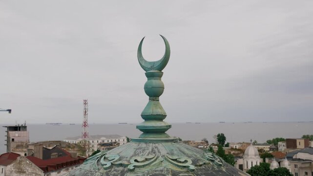 View of the crescent atop a mosque in Constanta, Romania, with the sea visible on the horizon
