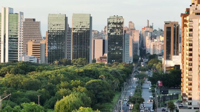 Telephoto parallax reveals Porto Alegre skyline above Parque Marinha and Borges de Medeiros Avenue traffic at sunset, 4K50.