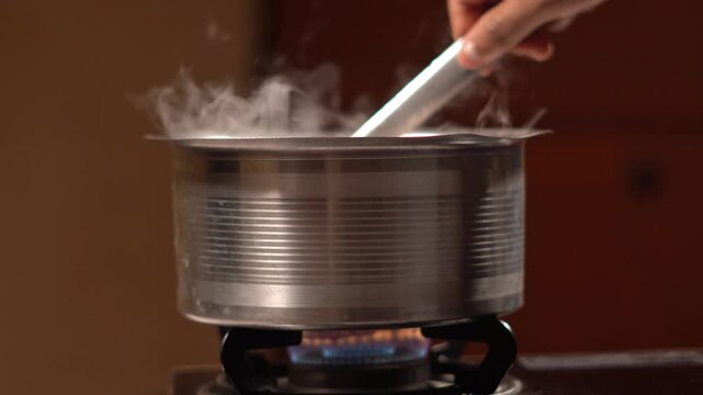Traditional Indian Cooking on Gas Stove. Indian Kitchen Scene. Indian Domestic Kitchen Cooking with Steam Rising. Authentic Indian Food Preparation on Gas Burner in North India.