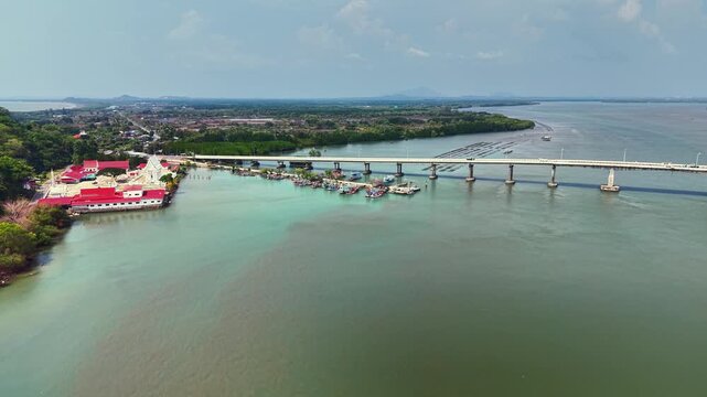 Aerial drone footage captured at 70&ndash;90 meters above Taksin Bridge in Laem Sing, Chanthaburi, Thailand. Filmed around 2 PM, showcasing the elegant bridge structure, clear roadway lines, and surrounding