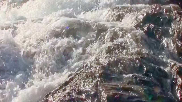 Sunlight glints off powerful cascades flowing over rocks in Letchworth State Park, New York. The water surges and foams as it descends, creating a dynamic, ethereal flow in the afternoon.