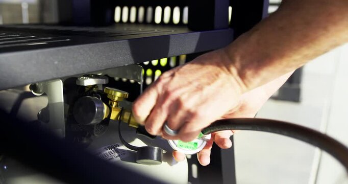 Hands of man attaching black gas hose to propane tank - steady cam