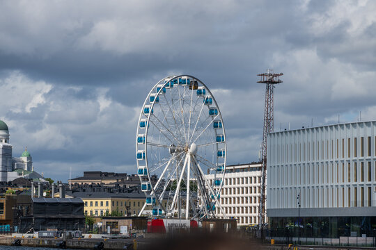 Helsinki, Finland - August 06 2025: Large ferris wheel by city waterfront skyline.