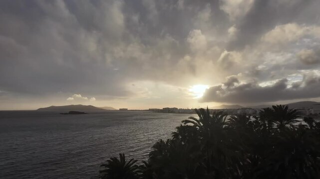 Timelapse in Ibiza in En Bossa beach in a winter day with a fast changing sky and the sun sinking in a golden horizon