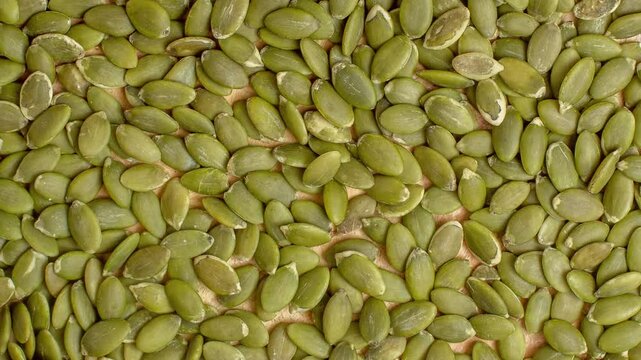 Close-up top view of green pumpkin seeds forming a natural textured background. Ideal for health, nutrition, vegan diet, organic food, and superfood concepts. Rich in protein, fiber, wellness themes.