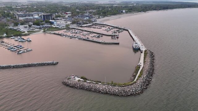 Drone aerial over Lake Winnipeg at Gimli Harbour, Manitoba, facing the town while slowly rotating right. Scenic waterfront marina and shoreline in the New Iceland community.