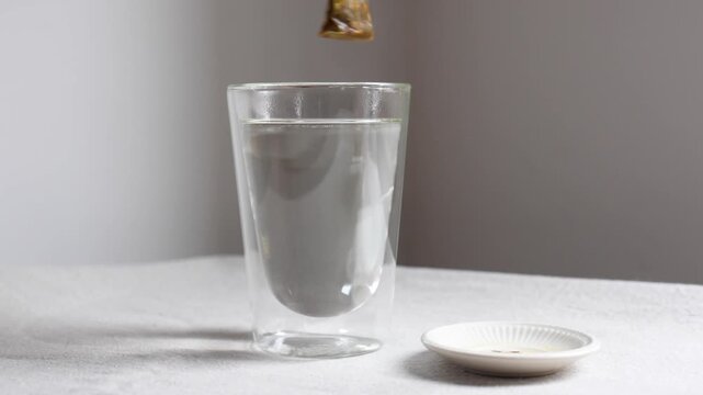Video of a teabag being put in a hot glass cup.