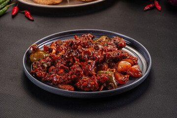 Spicy Indian chili dish with peppers and onions served on a gray plate