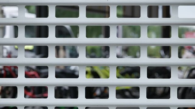 Geometric Pattern of a White Metal Roller Door with Defocused Urban Background