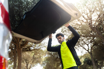 Man opening car trunk in a forest for adventure