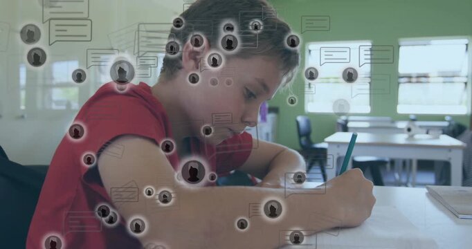 Schoolboy writing on paper in classroom, pencil touching page activating overlay icons for learning