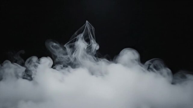 Dense white smoke or fog rising from a thick base against a dark black background, creating a mysterious and atmospheric effect.