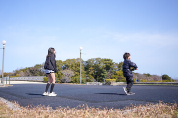 Obraz premium Two children are playing in a park. One of them is wearing a black jacket. The other child is wearing a black jacket and a backpack