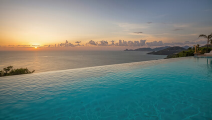Luxurious infinity pool overlooking ocean sunset with distant islands and palm trees