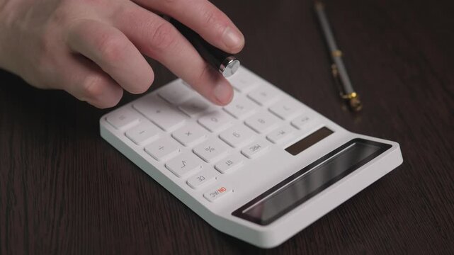 The white calculator on the dark table is close