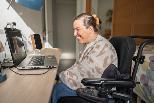 Woman smiling using assistive technology laptop for online communication