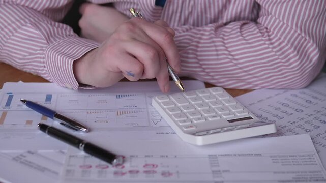 Analyst Reviewing Data. Professional Examining Charts And Preparing Detailed Audit Notes. Business Analyst Pressing Calculator Keys While Reviewing Charts And Drafting Audit Documentation