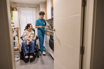 Obraz premium Caregiver cooking for woman with disability in kitchen