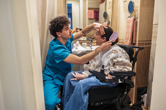 Caregiver assisting woman in wheelchair with personal grooming