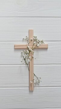 Wooden vectical cross decorated with gypsophila flowers on a white background for easter celebrations and good friday