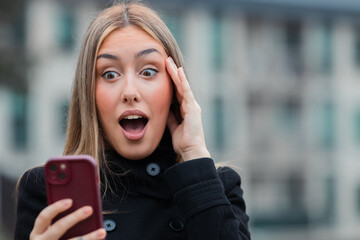 young woman looking at her mobile phone with a surprised expression