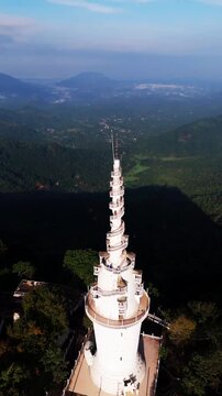 Cinematic aerial view of Ambuluwawa Tower in Kandy &ndash; Iconic white spiral architecture rising above misty mountains in Sri Lanka