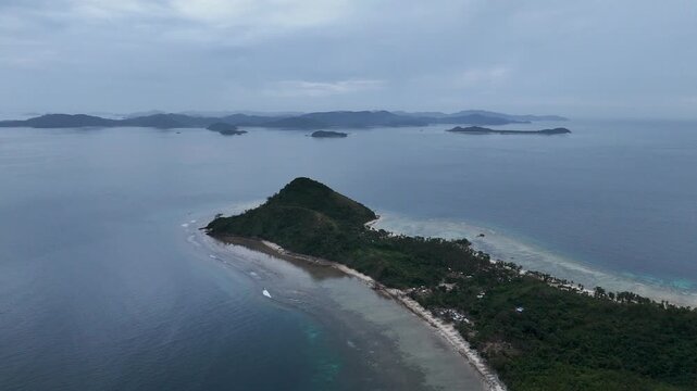 Drone aerial view of Bayang Basecamp or Calibangbangan Camp and turquoise reef along Calibangbangan Island coastline between Coron and El Nido, Palawan, Philippines.
