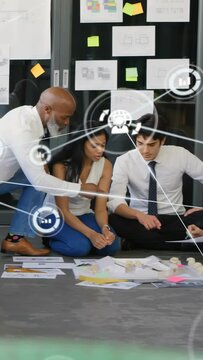 Vertical video: Design team kneeling, mentor pointing papers, reviewing plans, overlay showing flow