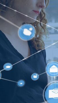 Vertical video: Woman tapping device in office causing icons and lines overlaying face for business