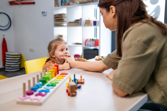 Speech therapist assisting a young girl with oral motor exercises, promoting improved speech development and communication skills during an education session in a learning environment