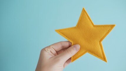 Obraz premium Hand Holding Golden Star on Blue Background Representing Achievement, Success, Rating Concept, Excellence Award and Positive Feedback Symbol
