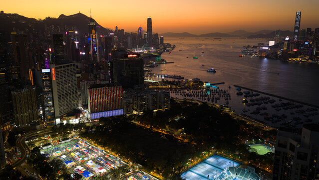 Hong Kong, Hong Kong - 14 February 2026: Aerial view of Victoria Harbour's shimmering waters reflecting the city's vibrant lights, juxtaposed against the dark silhouettes of distant mountains.